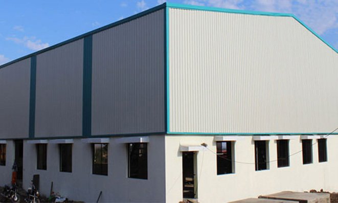 Pre-engineered factory shed with metal wall cladding over a masonry base
